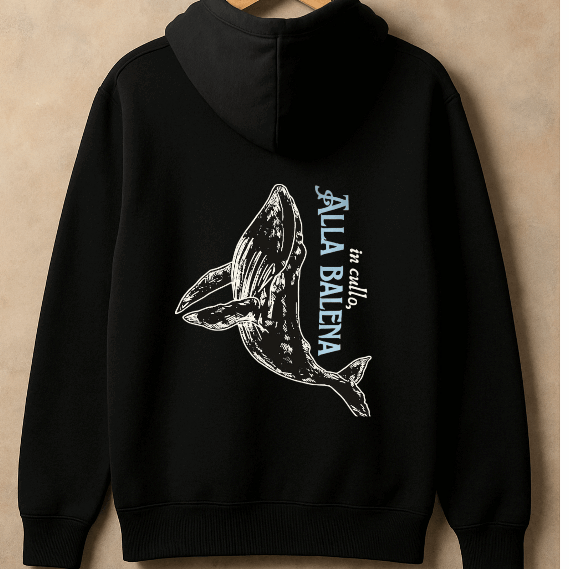 Black hoodie with whale graphic and text on a beige background