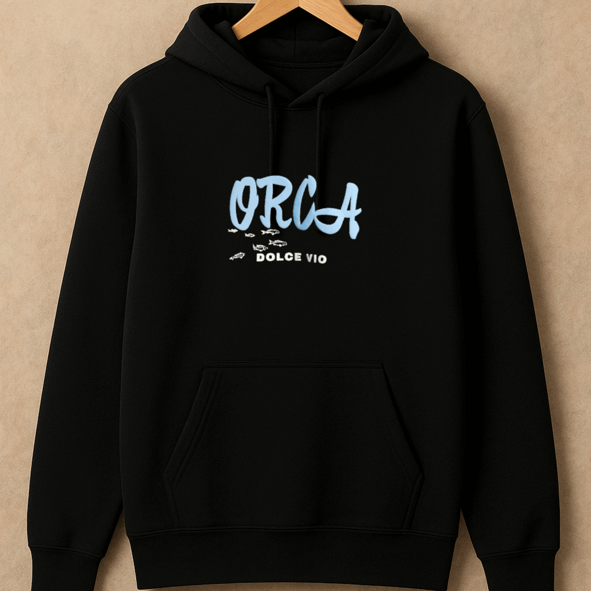 Black hoodie with 'ORCA' logo on a beige background
