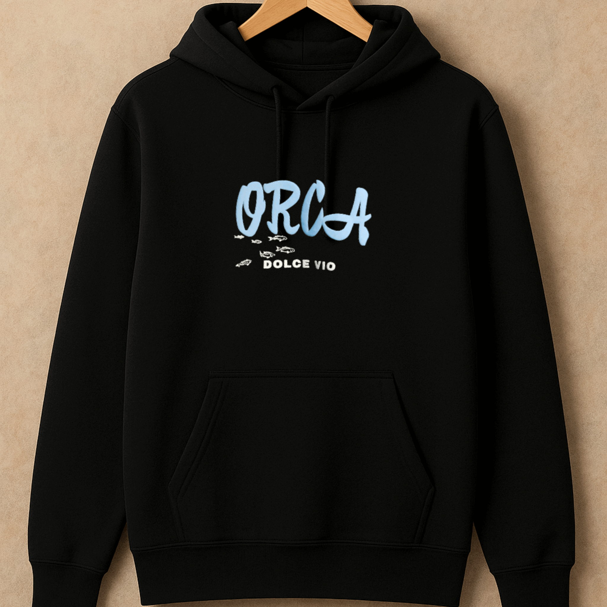 Black hoodie with 'ORCA' logo on a beige background
