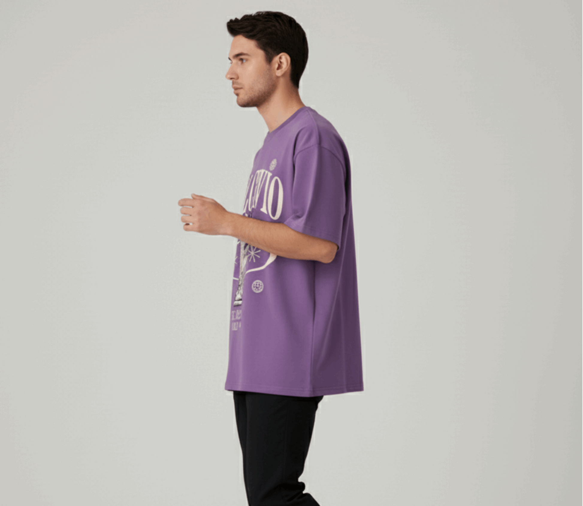 Man wearing a purple t-shirt with text, black pants, and white shoes on a light gray background