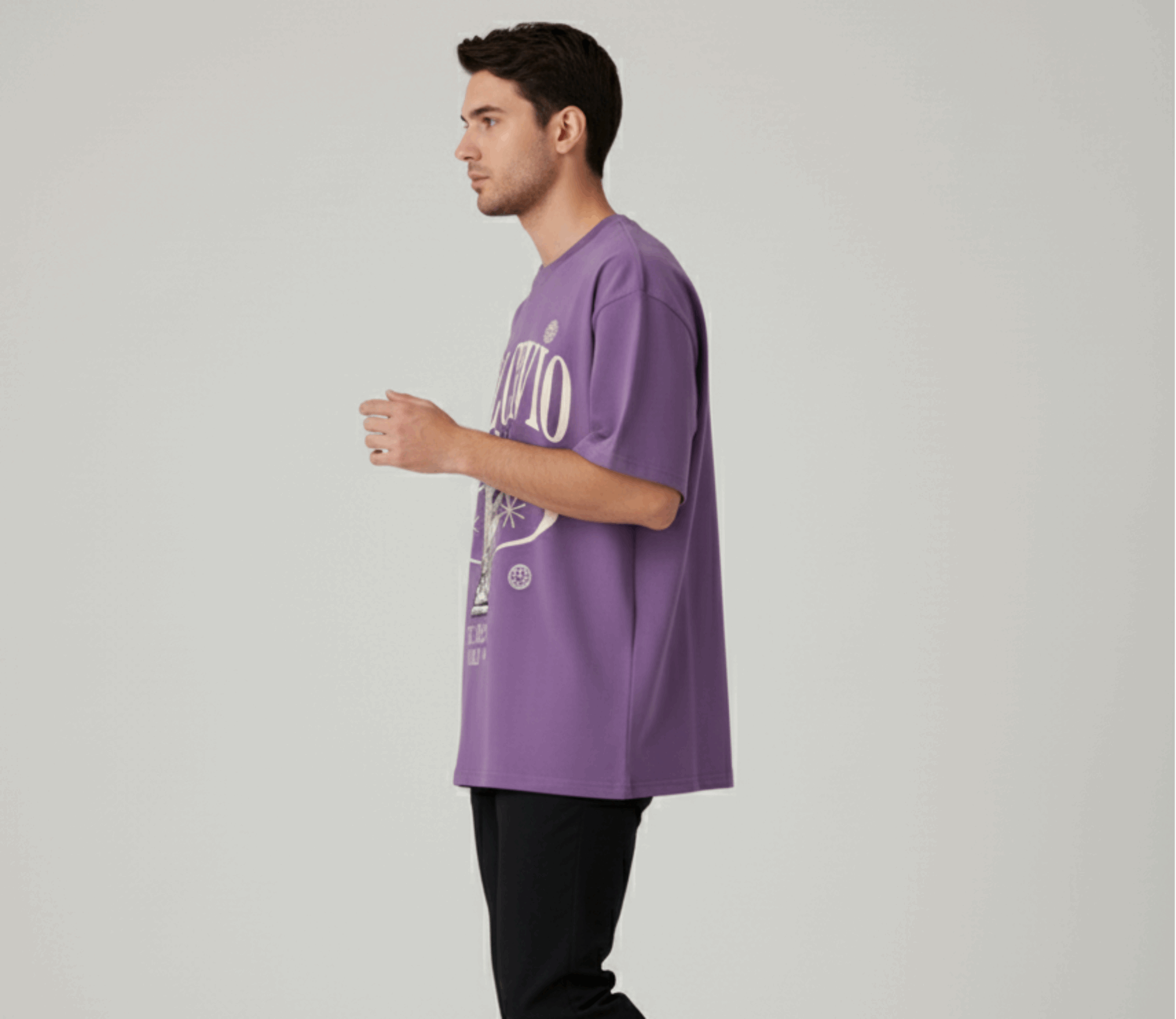 Man wearing a purple t-shirt with text, black pants, and white shoes on a light gray background