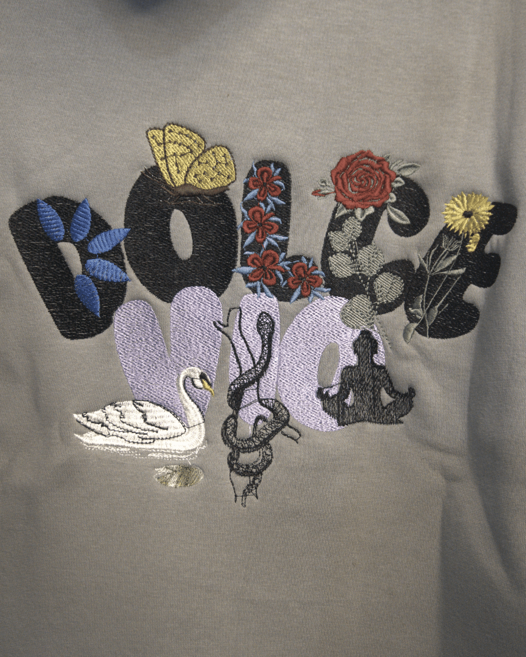 Embroidered design on a gray fabric with various symbols and patterns.